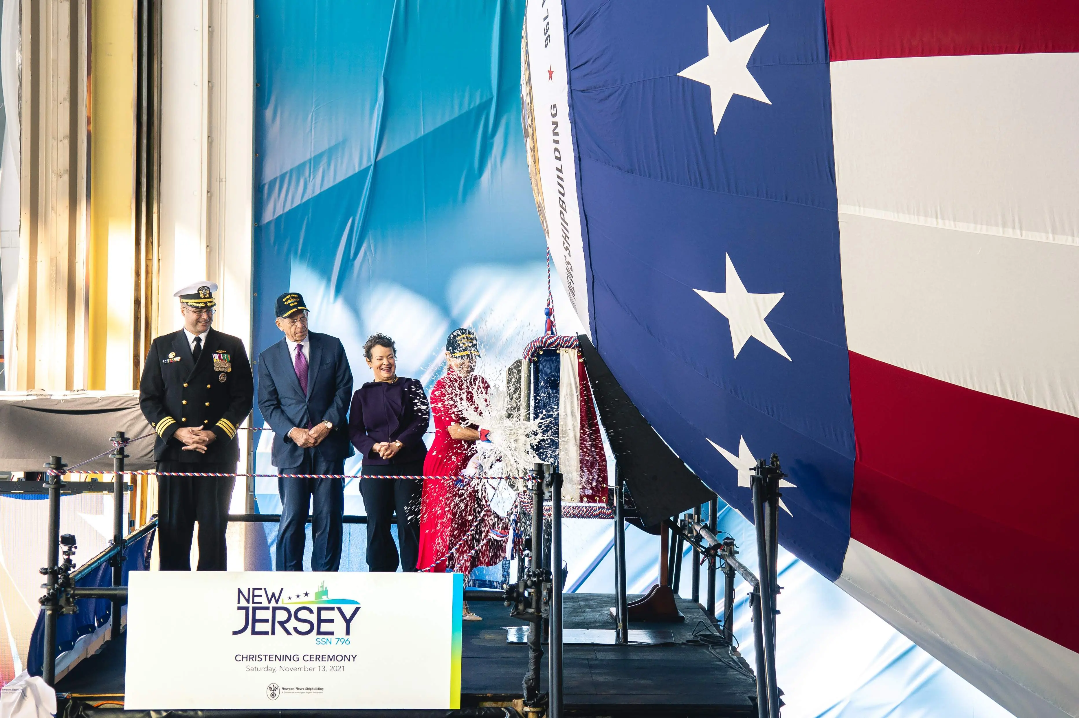 Ship's sponsor Susan DiMarco christening PCU New Jersey (SSN-796) at Newport News Shipbuilding on November 13, 2021, with prospective commanding officer Cmdr. Carlos Otero, retired Adm. Michael Mullen, and Newport News Shipbuilding president Jennifer Boykin looking on.