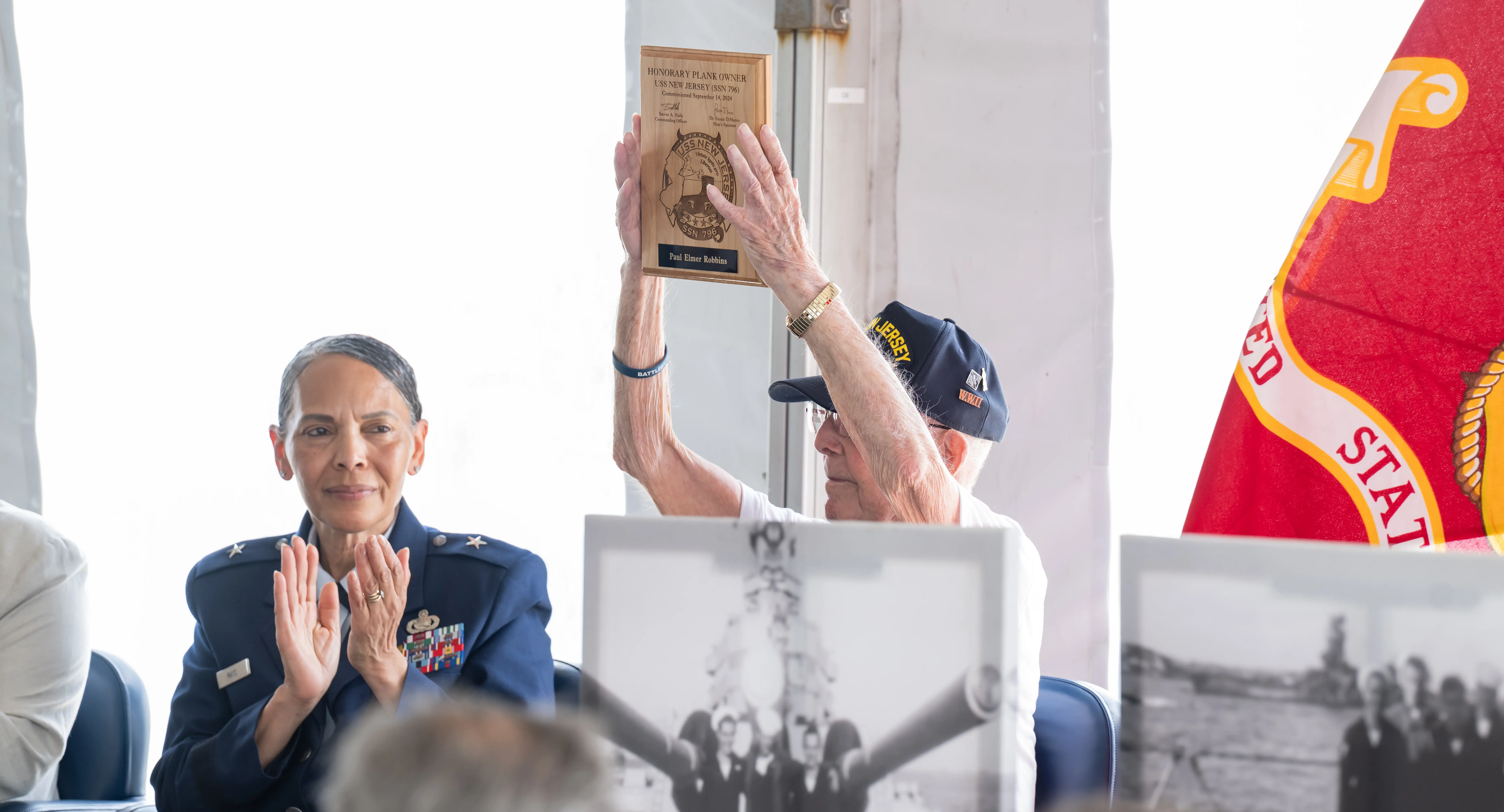 Paul Robbins, 101, raises his Honorary Plank Owner plaque overhead aboard Battleship New Jersey.