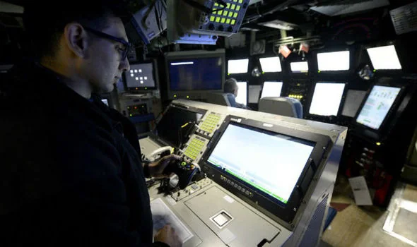 A Sailor mans the photonics mast controller aboard a Virginia-class submarine.